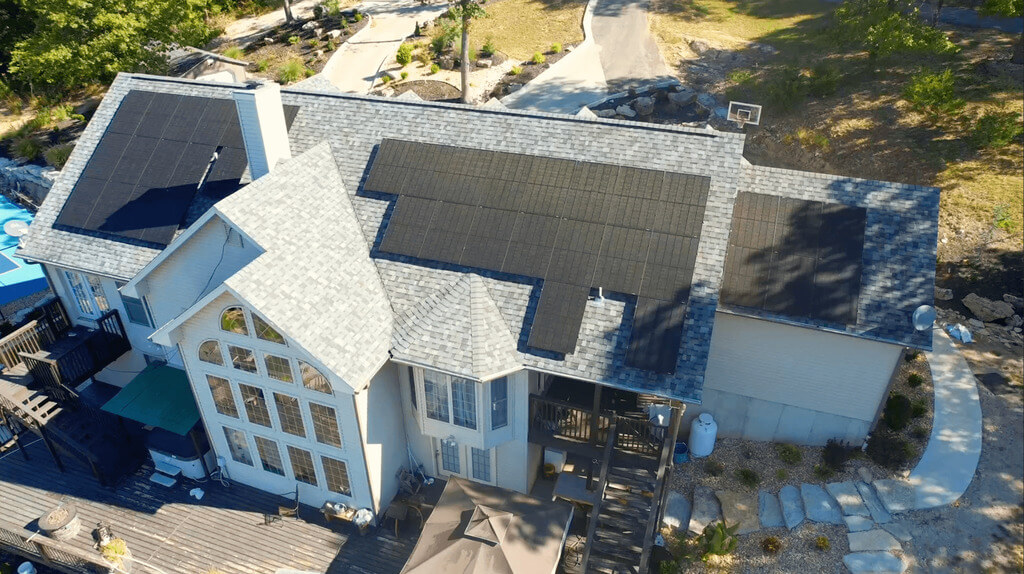 An aerial view of a house with a solar panel on the roof