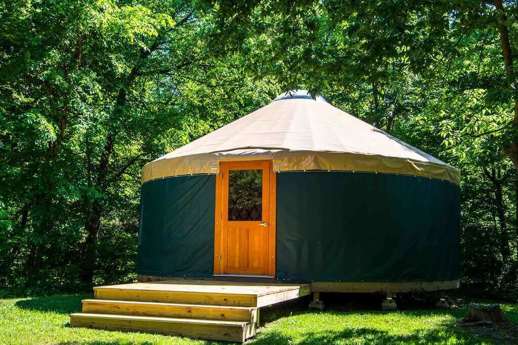 A yurt in the woods with steps leading up to it
