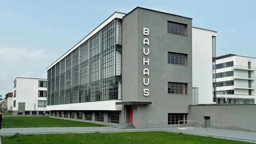 grey Bauhaus Architecture with a red door in front of it
