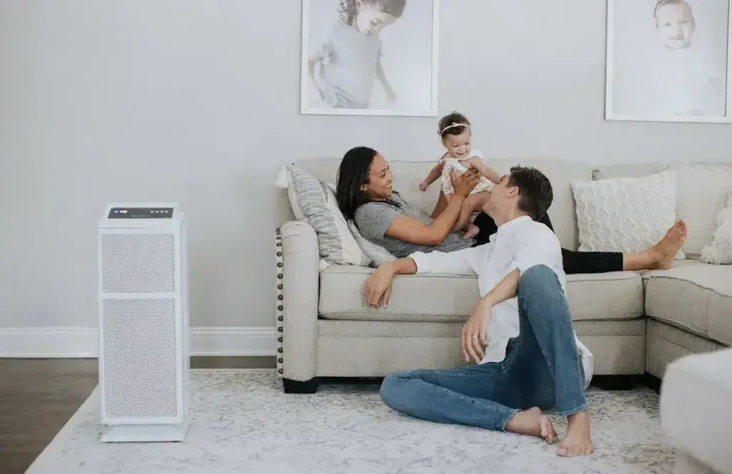 A man and woman playing with a child on a couch 