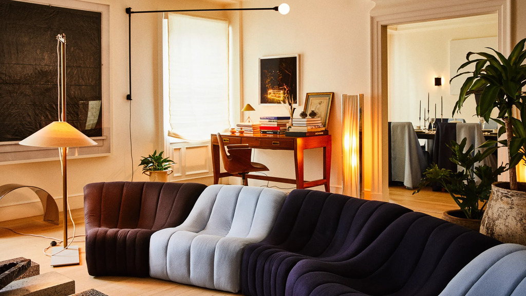 A living room with different color couches and a desk

