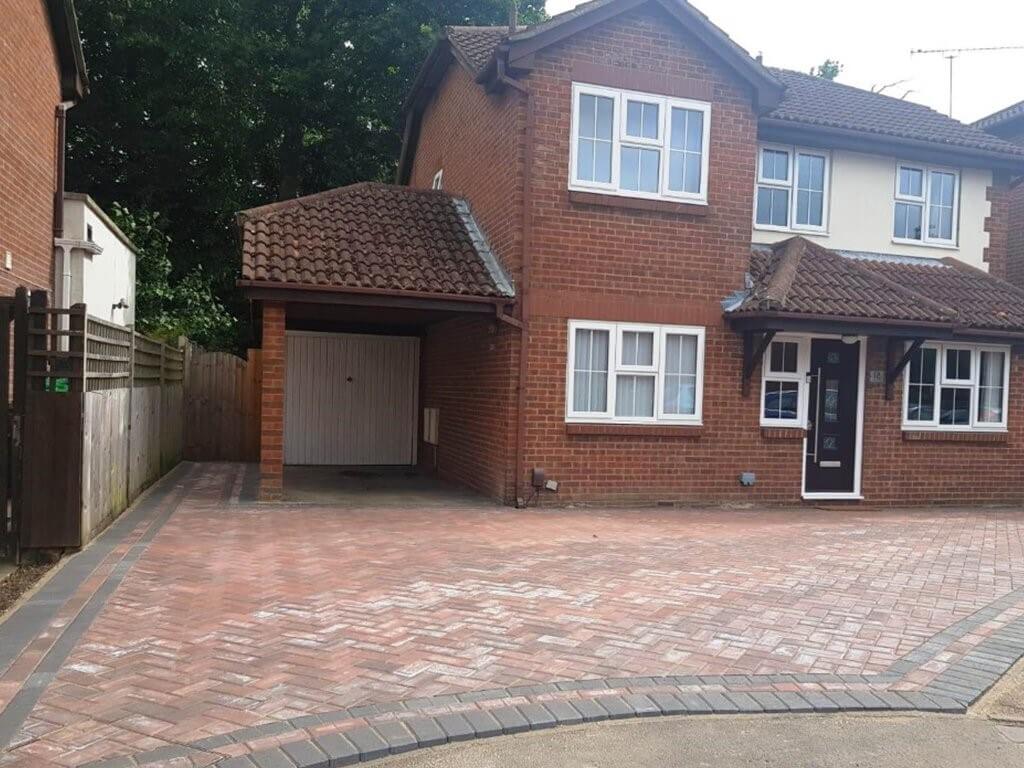 A brick driveway with a gate and a house 
