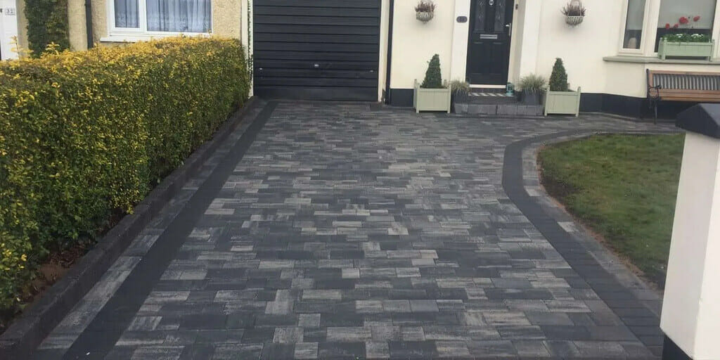 A house with a black door and a brick driveway
